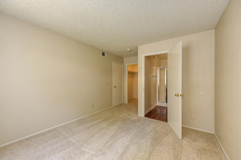 Empty Bedroom with Carpet, Open Bathroom Door, and Closet